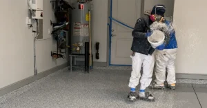Installer broadcasting color flake into a wet epoxy base coat during a garage floor installation